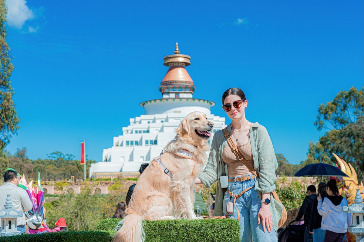 A young woman with a dog, with a Buddhist temple in the background