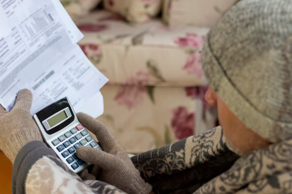 person with a calculator and bills and wearing gloves and a beanie