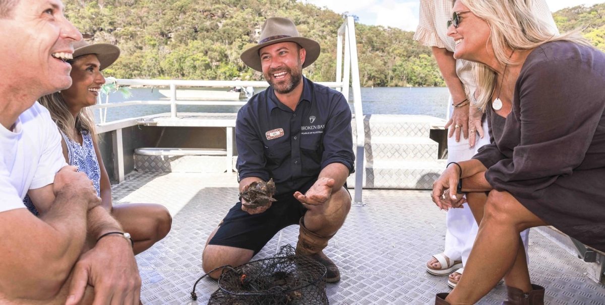A tour guide showing people an oyster catch on a boat on a river