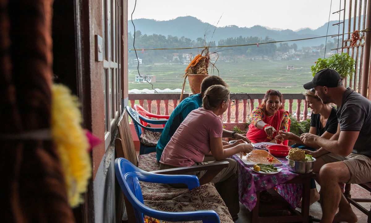 A group of people having a meal on a deck with countryside in the background