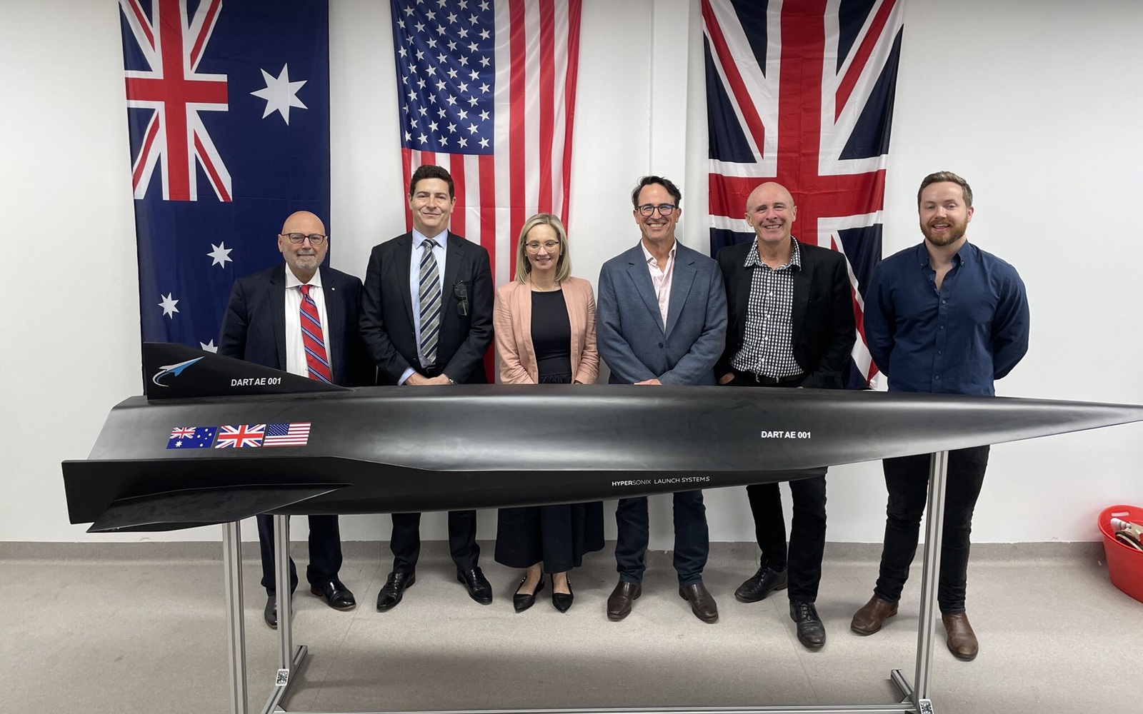 six people with a model of a hypersonic aircraft