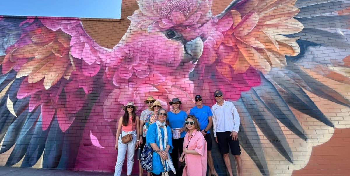 people standing in front of a giant mural of a bird