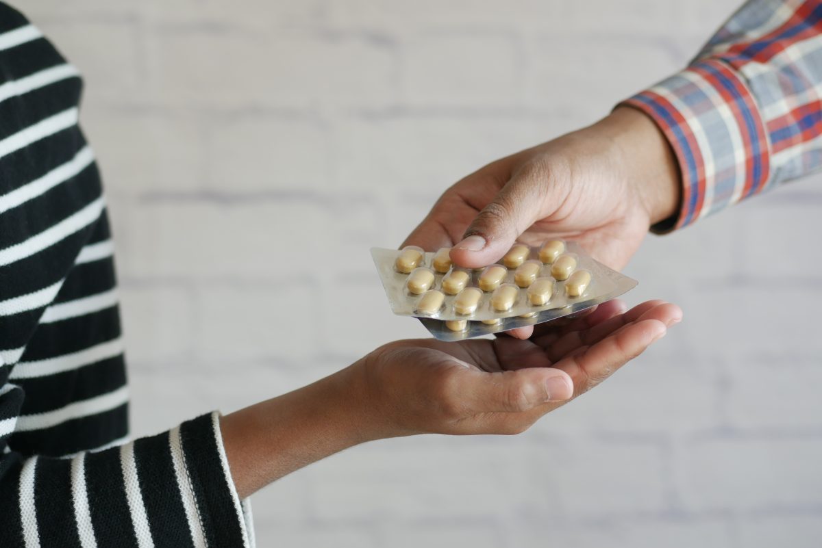 A person giving pills to another