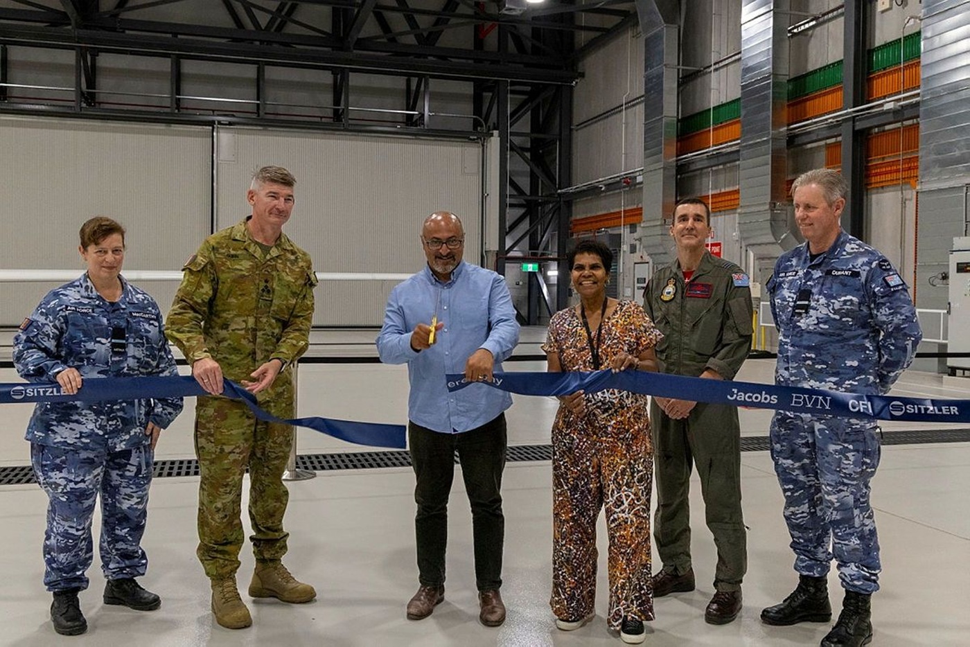 a man and defence personnel officially opening a maintenance facility