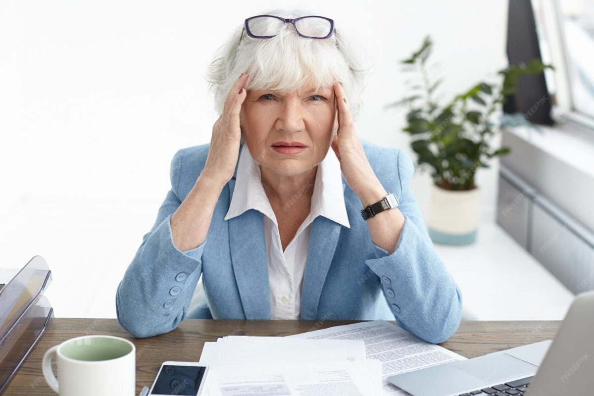 Unhappy older woman at desk.