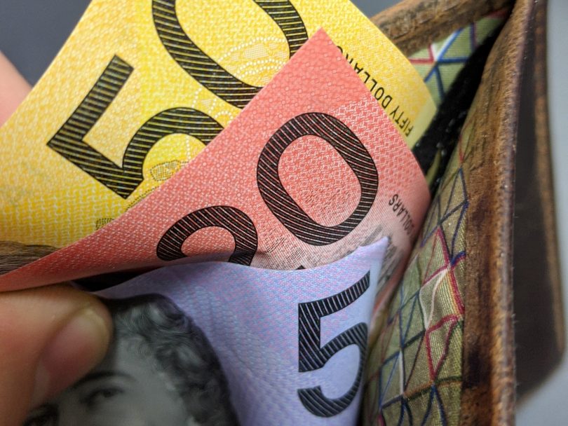 A hand takes several notes of Australian currency from a wallet