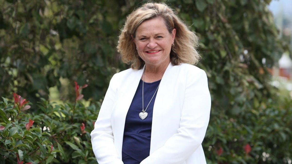 A smiling woman in a white blazer
