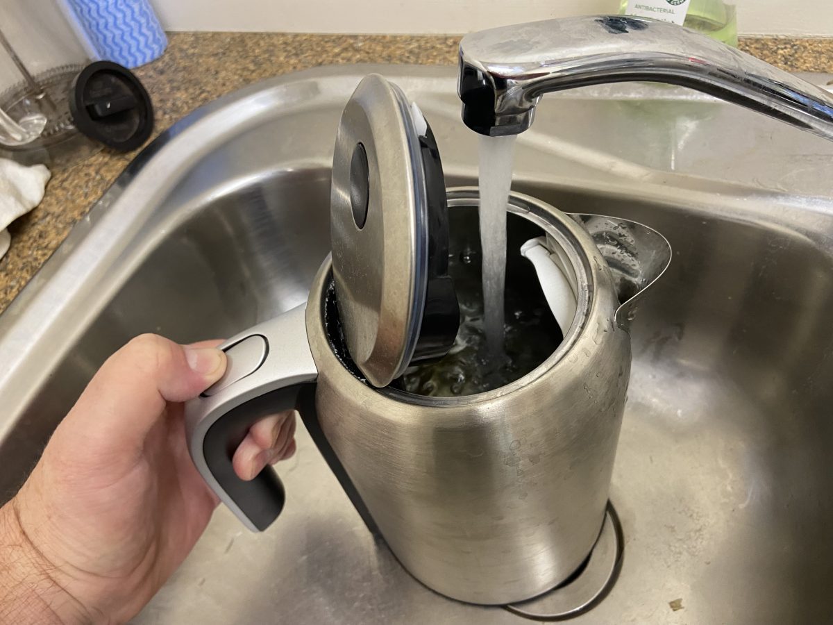 A person pouring tap water into a kettle