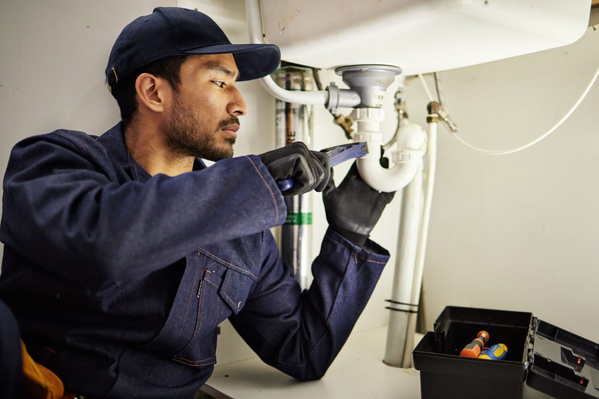 plumber in uniform under sink