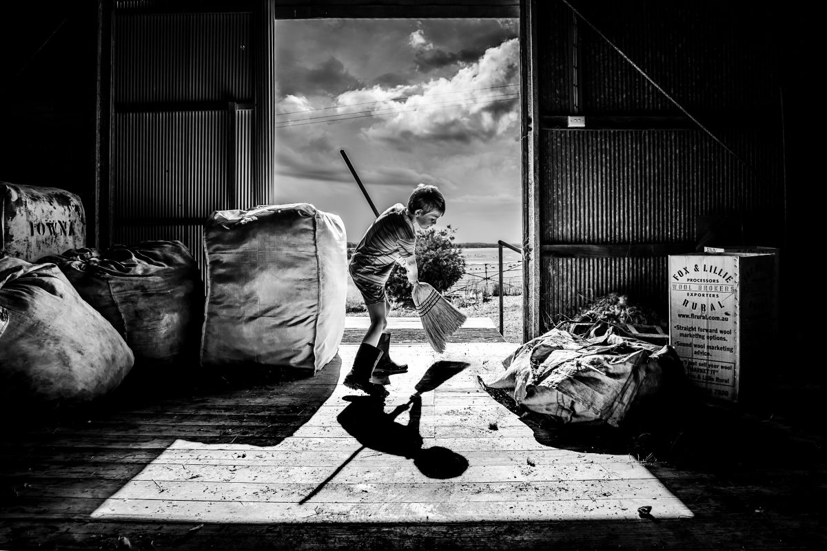 boy sweeping woolshed